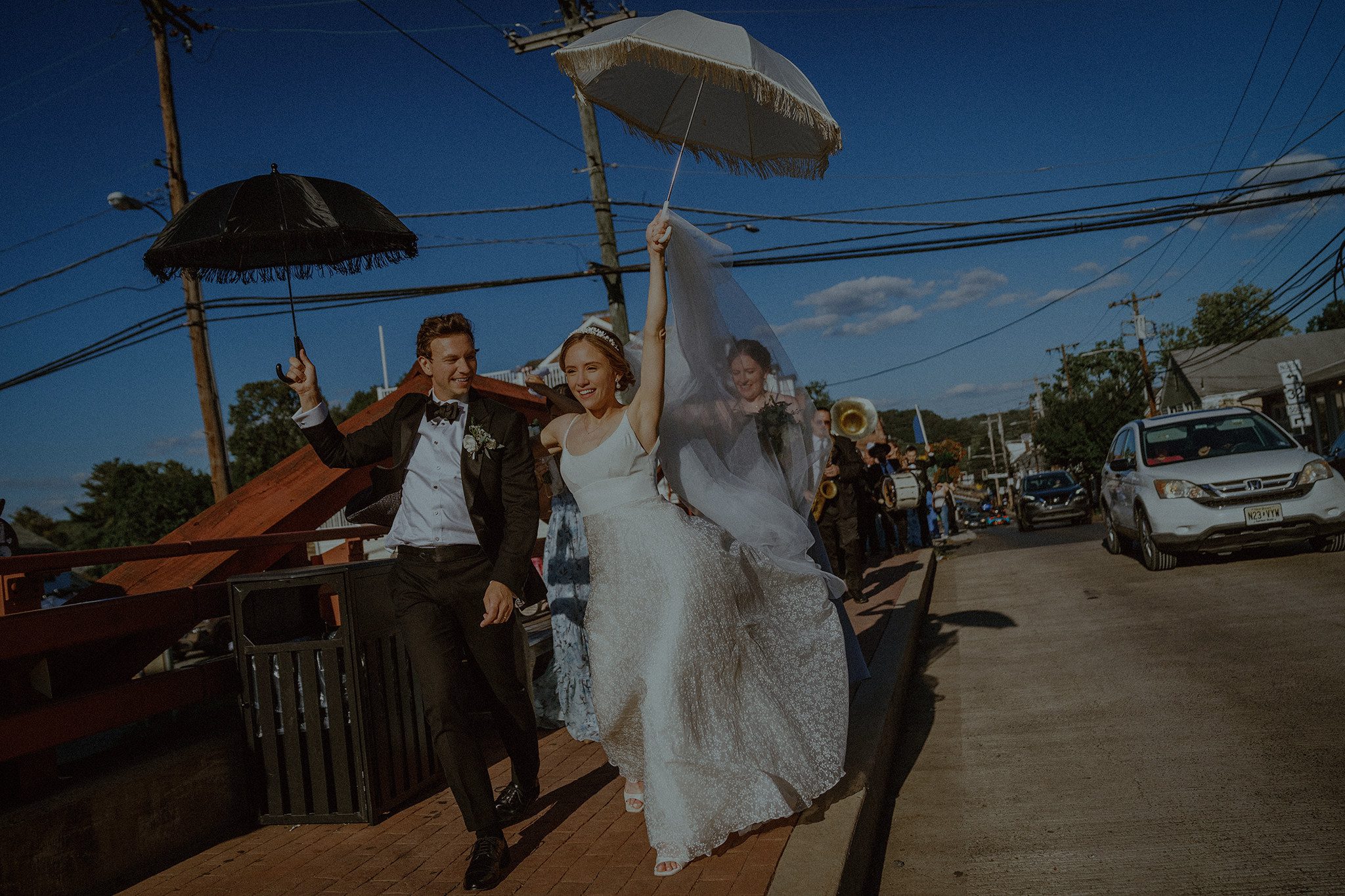 Candid fine art wedding photography capturing a joyful second line parade with the bride and groom celebrating under umbrellas — vibrant, cinematic storytelling by Resonance Vision.
