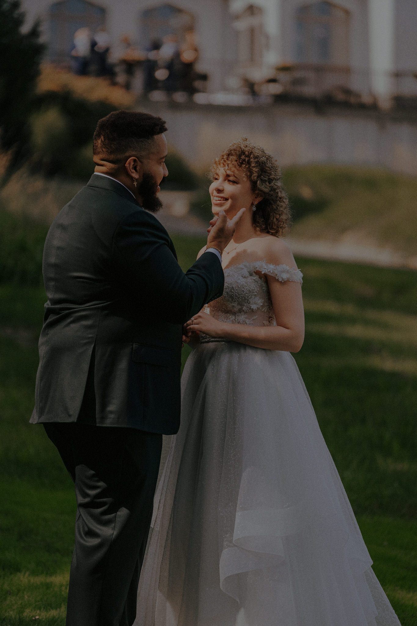 Intimate candid moment of the groom gently touching the bride’s face, photographed in a warm, cinematic fine-art style by Resonance Vision.
