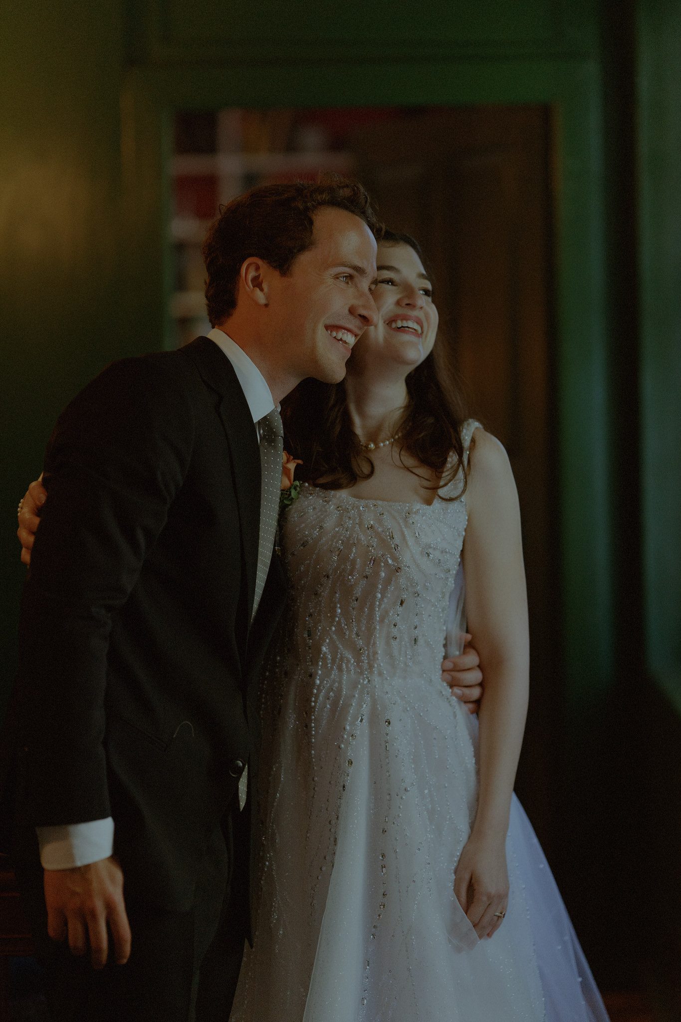 Emotional candid moment of a bride and groom smiling together indoors, captured in a soft, cinematic fine-art style with warm, nostalgic tones.