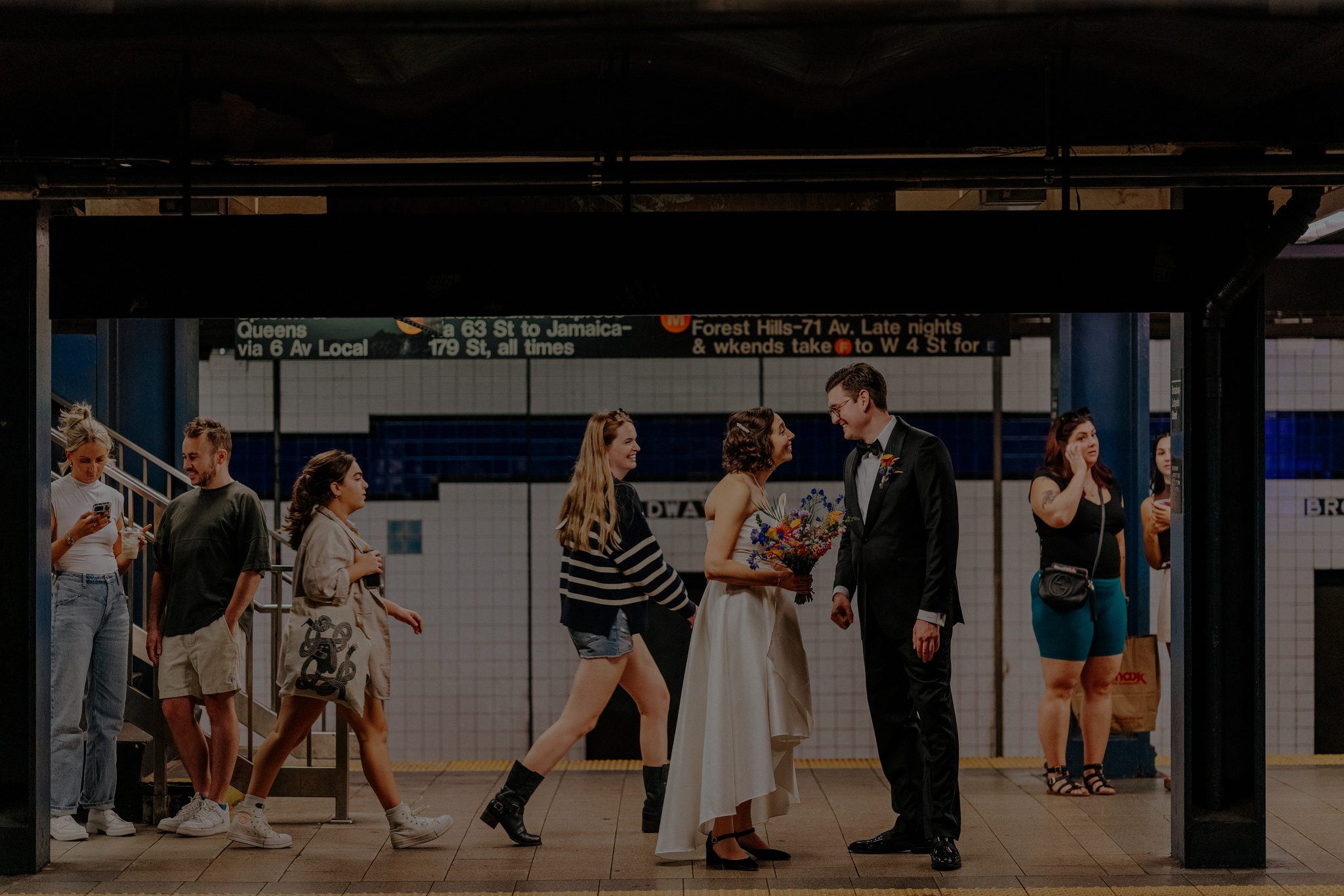 Authentic NYC subway wedding moment with the couple smiling at each other on the platform, blending candid storytelling with cinematic city atmosphere.